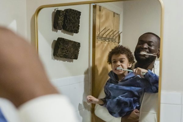 Black father and son brushing teeth in bathroom