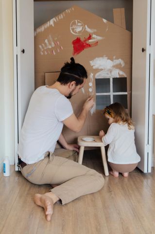 Father and Daughter Painting a Cardboard House Together